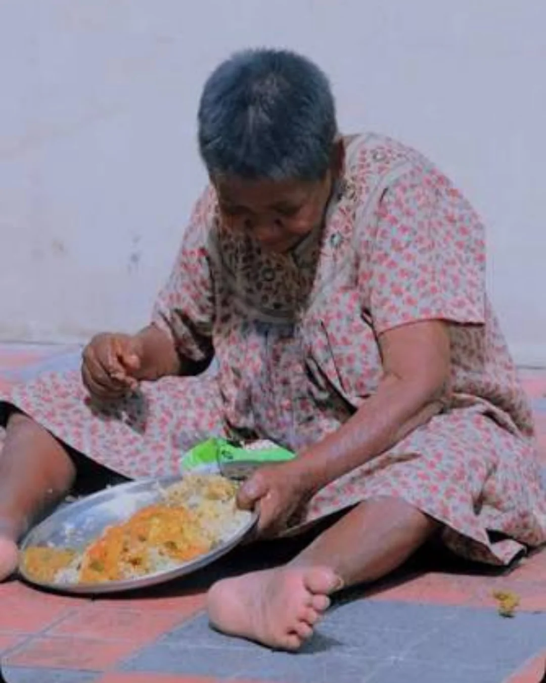 An elderly woman eating a prepared meal