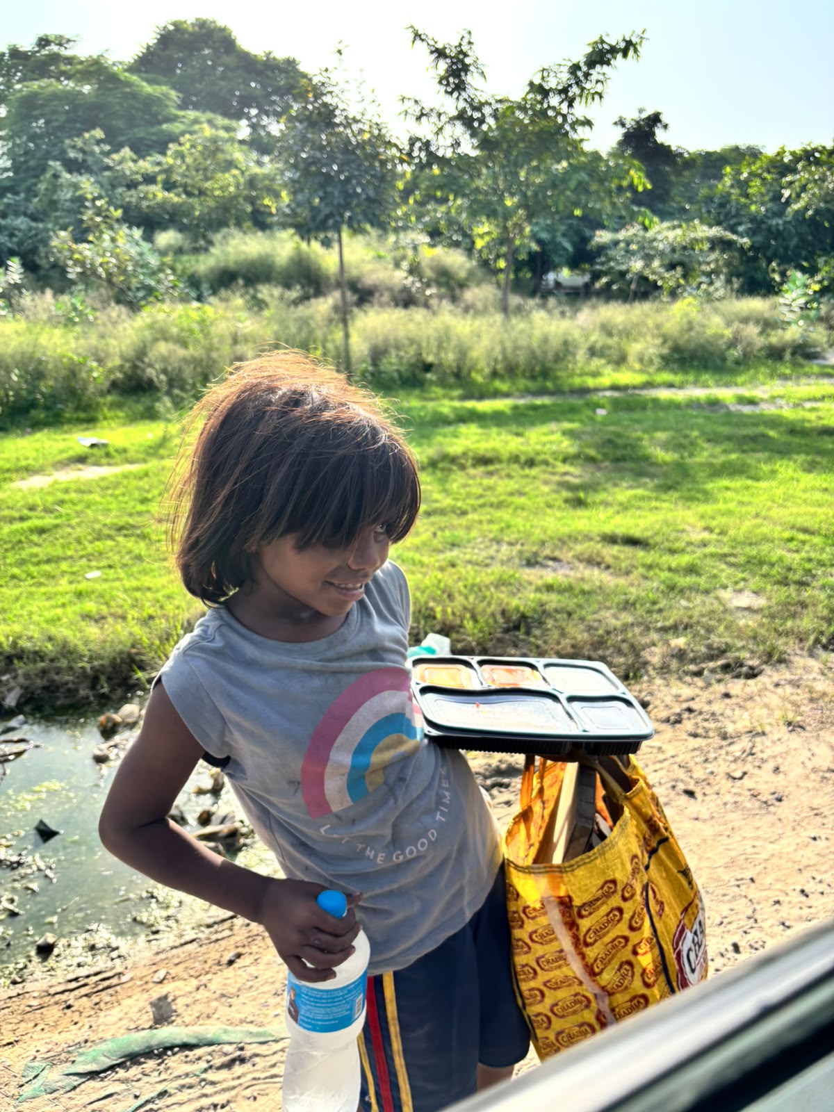 A child receiving a prepared meal and drinking water during food seva